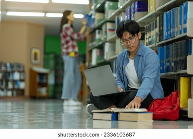 College student studying with a laptop in a library